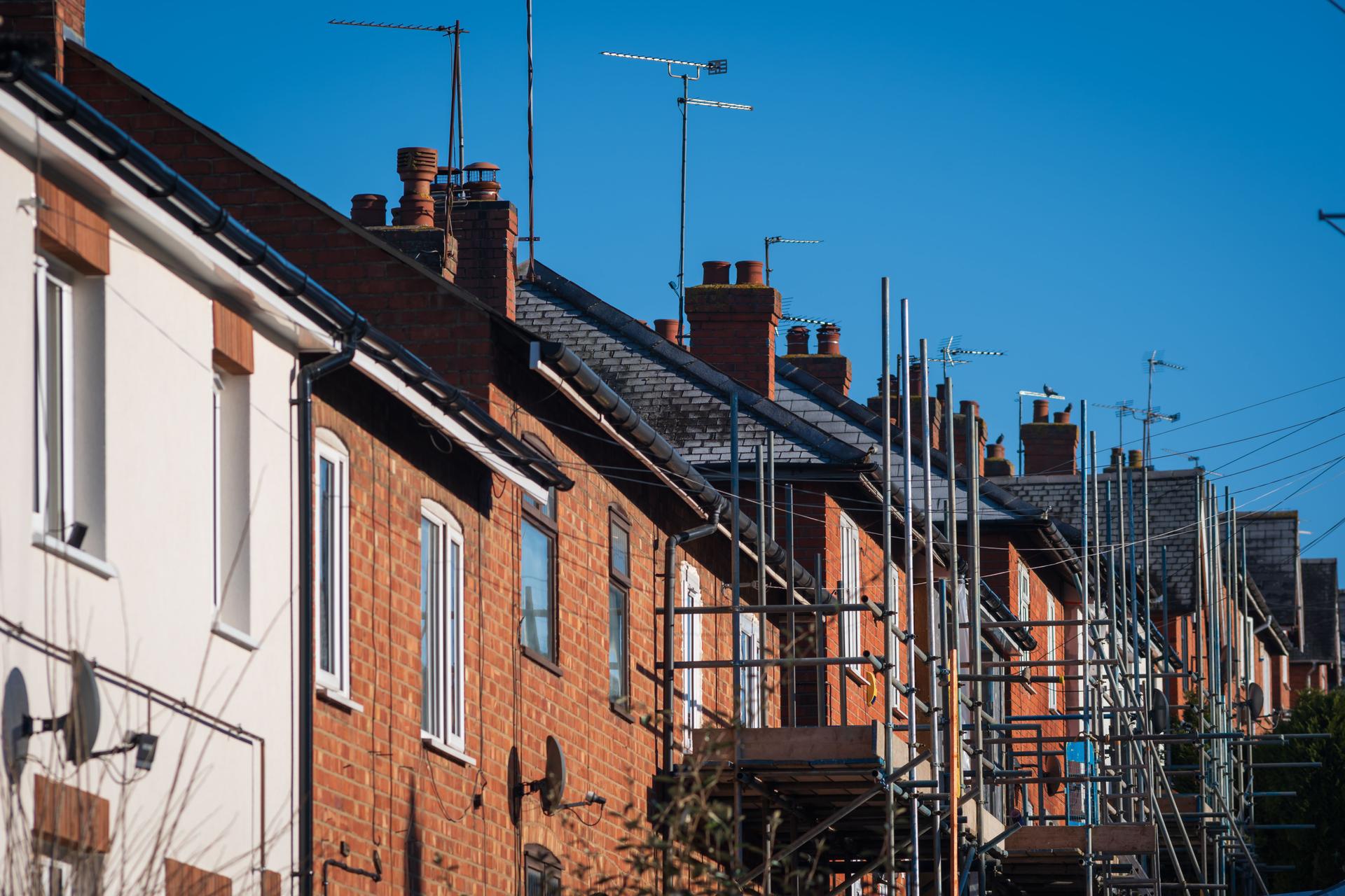 Row terrace red brick houses during external insulation works in england uk.