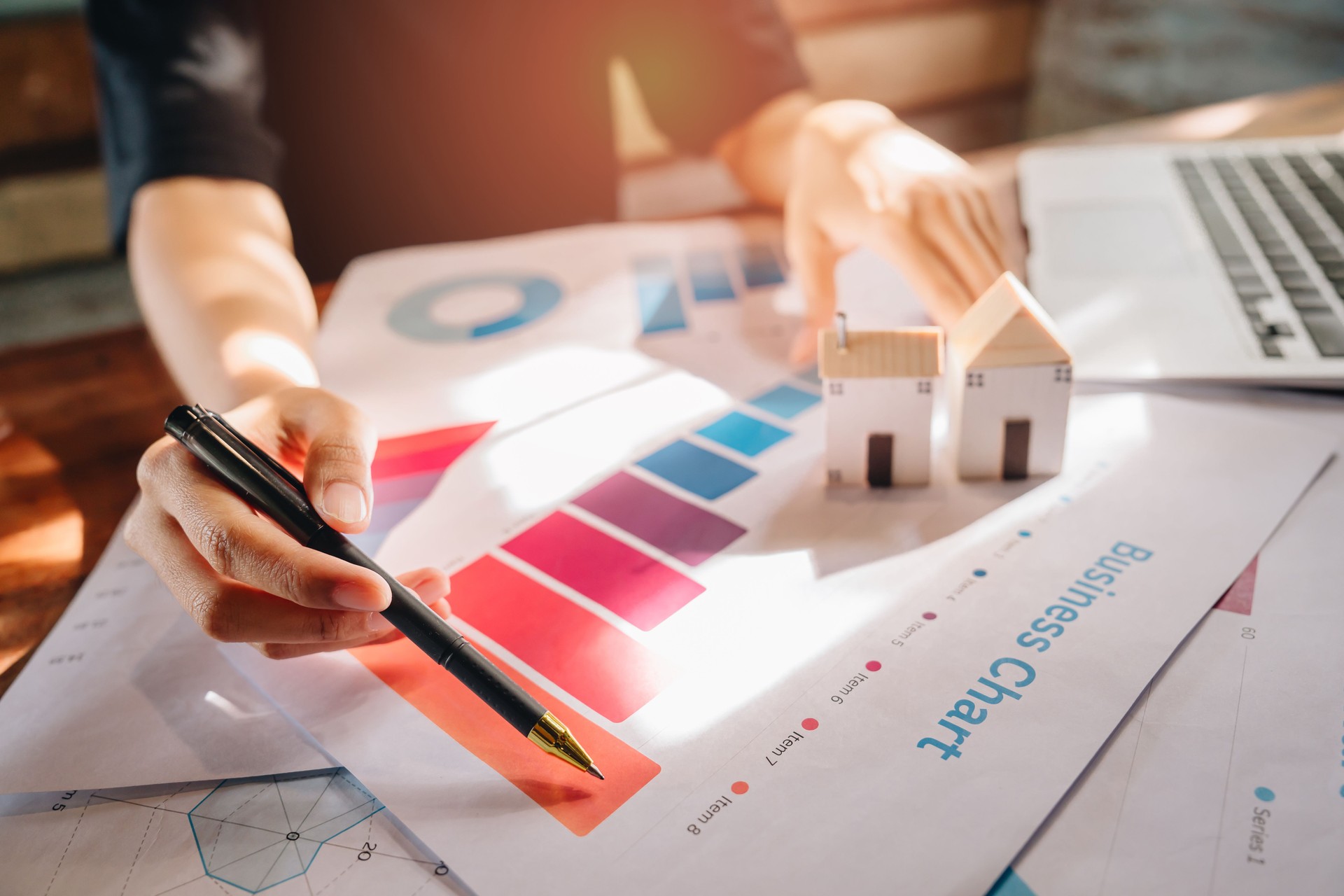 Real estate concept. Analysis of Business Charts with Model Houses on Table for Real Estate Investment Strategy and Financial Planning